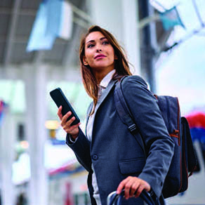 Business woman looking up from her phone as she walks through airport