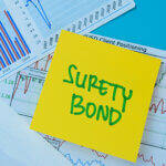 Post it note with the words, "Surety bond" written on it on top of a stack of graphs