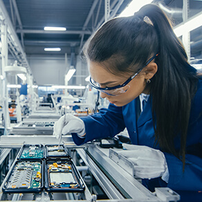 Woman working in a factory assembly line working closely with an electronic piece of equipment