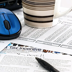 Tax incentive form written in black pen with striped coffee cup and blue mouse