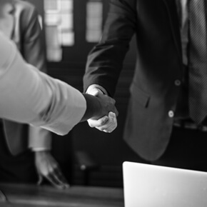 Two men shaking hands one with suit jacket and one without