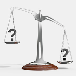 Silver balancing scall with brown bottom and a question mark on the raised end and question mark on the lower