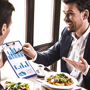 Businessmen at dinner discussing charts looking happy