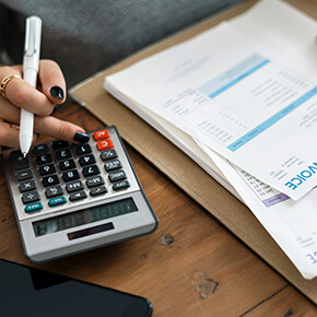 Woman looking at invoice papers while using calculator