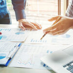 two people discussing papers with charts and graphs on them