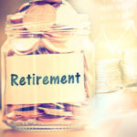 Glass jar with gold coins inside and retirement written on a piece of paper attached to jar