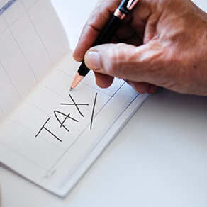 Man writing the word tax in calendar book