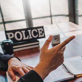 Hand pointing out of frame with papers on table and sign that says police