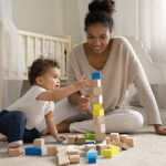Woman in front of crib playing with blocks with baby