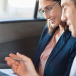 Business woman in vehicle or plane looking down at her phone with man looking on