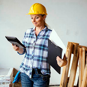Professional female carpenter calculating and checking documents in workshop.Woman planning the job looking at calculator.Copy space