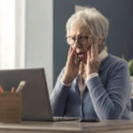 Shocked woman with hands up by her face looking at her computer screen