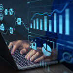 Hands typing on a keyboard in the dark with images of graphs overlaid on the photo