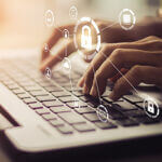 Hands typing on a laptop with computer image lock overlaid on the image