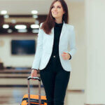 Business Woman with Travel Trolley Luggage in Hotel Lobby. Female executive with suitcase in work related business trip