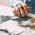 Healthcare costs and fees concept.Hand of smart doctor used a calculator for medical costs in modern hospital