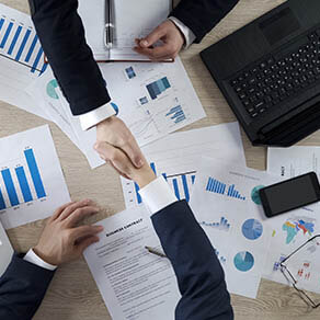 Business partners shaking hands, signing business contract after negotiations