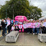 Employees at Making Strides Walk in front of the big pink chair.