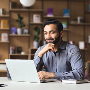 Man working on a laptop with chin resting on his hand