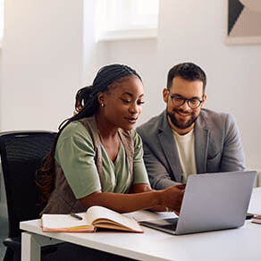 Couple sitting side by side looking at something on a laptop