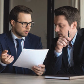 Two business men at a table in discussion at a table looking at a document