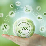 Hand holding glass ball with green tax icons