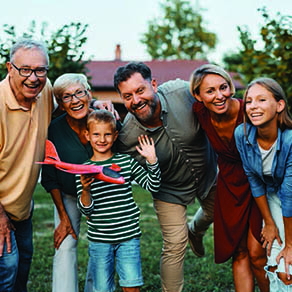 Family of four with their grandparents posing outdoors for a photo